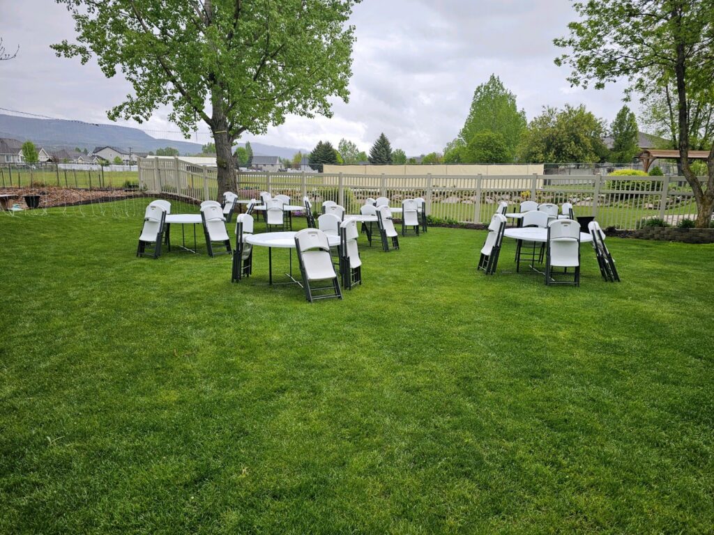 Tables with chairs stacked and leaning in backyard
